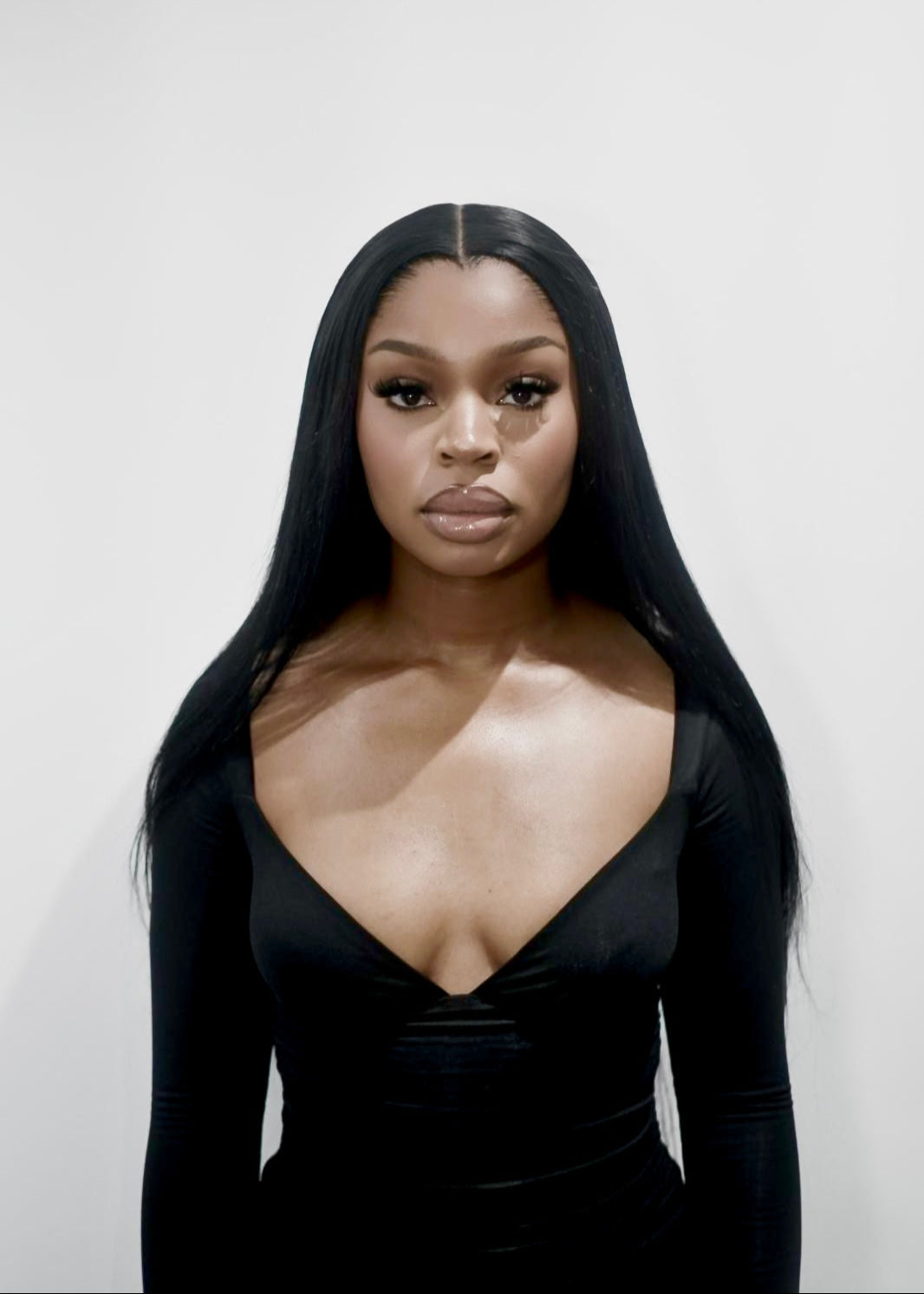 Woman wearing a black dress with a plunging neckline against a plain background